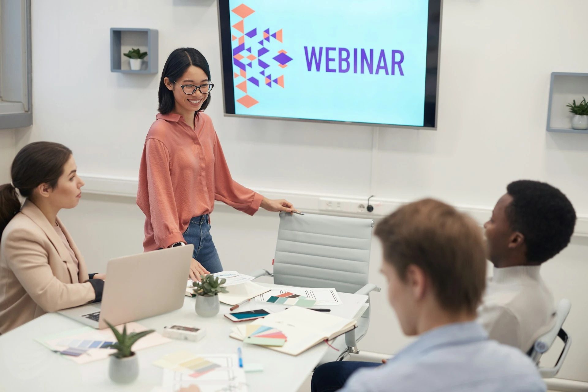 Una relatrice presenta un webinar davanti allo schermo a un gruppo di colleghi